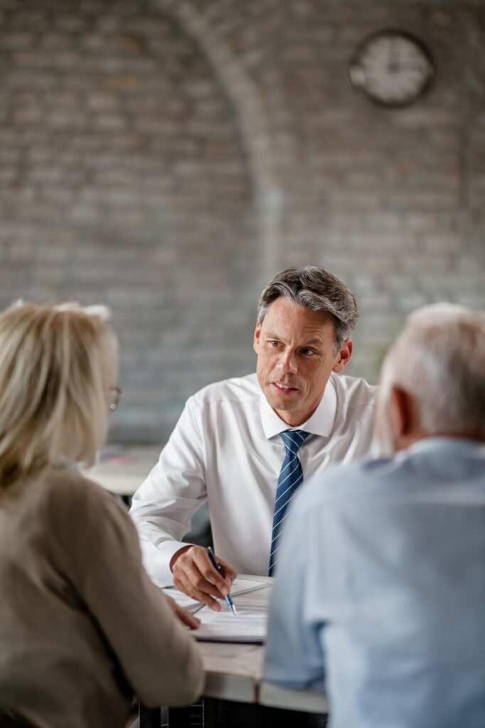 Bank manager and senior couple going through financial reports during a meeting.